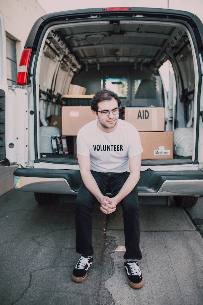 creative-02 A volunteer sits in front of a supply-filled van, ready for aid distribution.