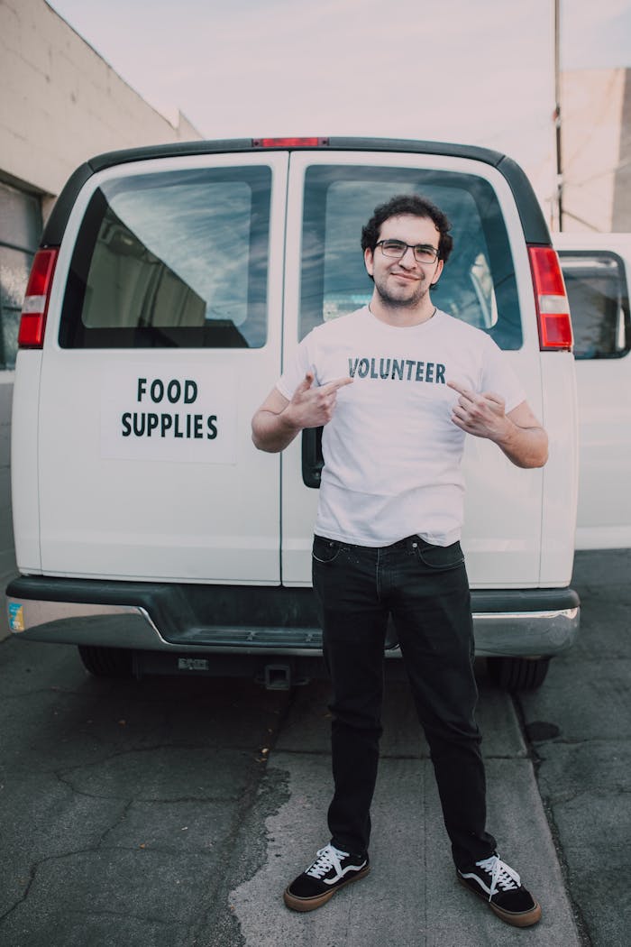 Man standing in front of a food supplies van, promoting volunteerism.